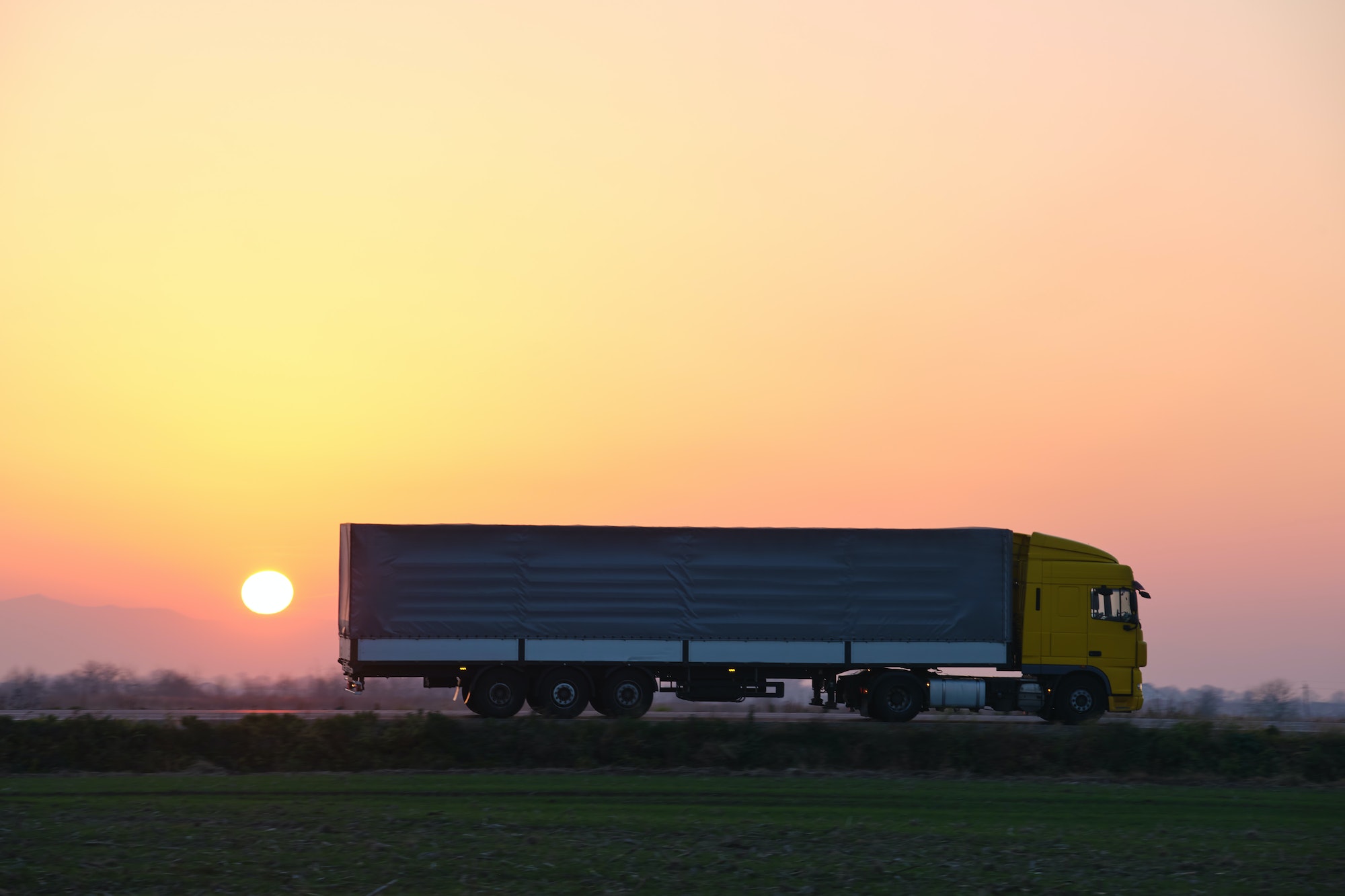 Semi-truck with cargo trailer driving on highway hauling goods in evening. Delivery transportation