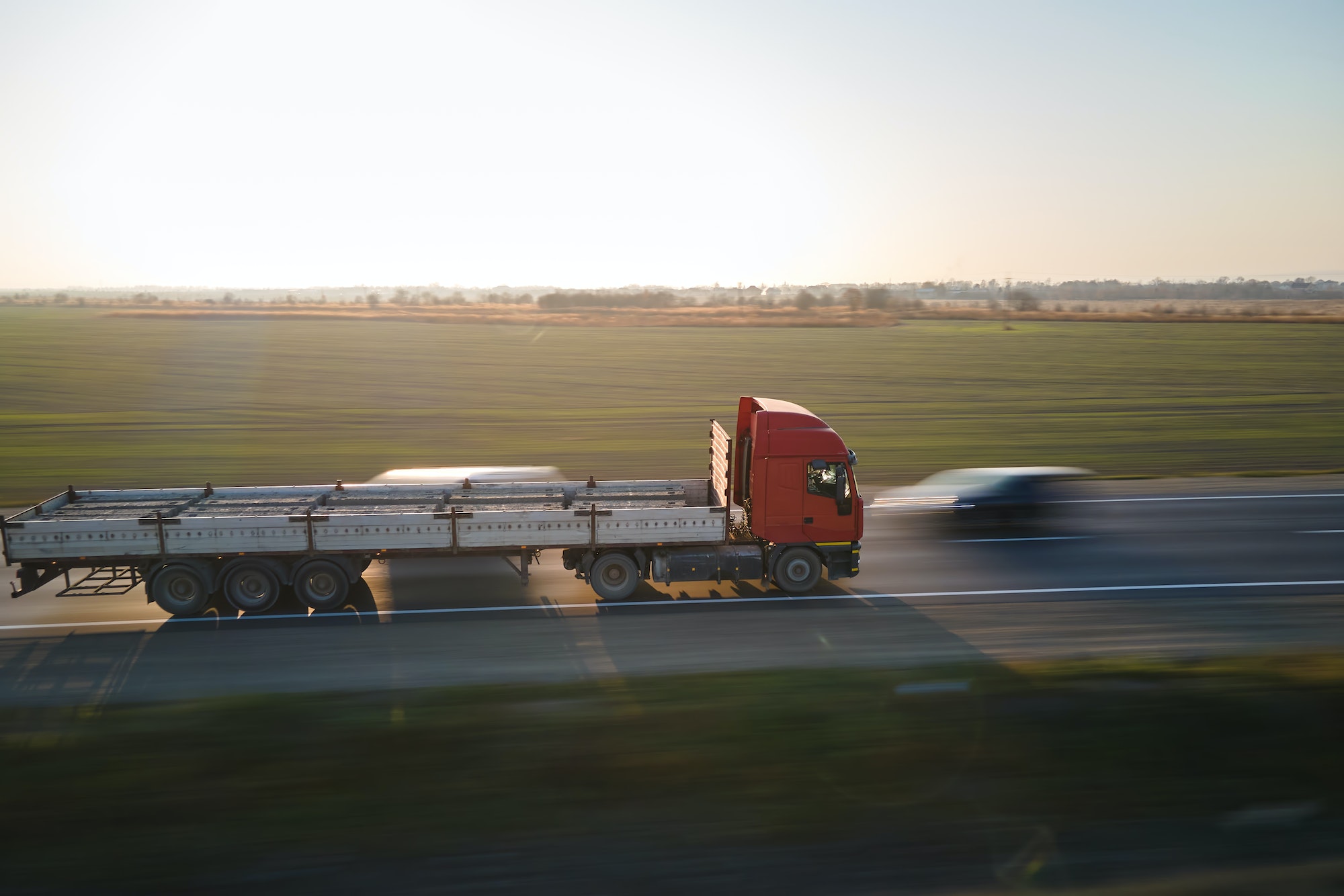 Aerial view of blurred fast moving semi-truck with cargo trailer driving on highway