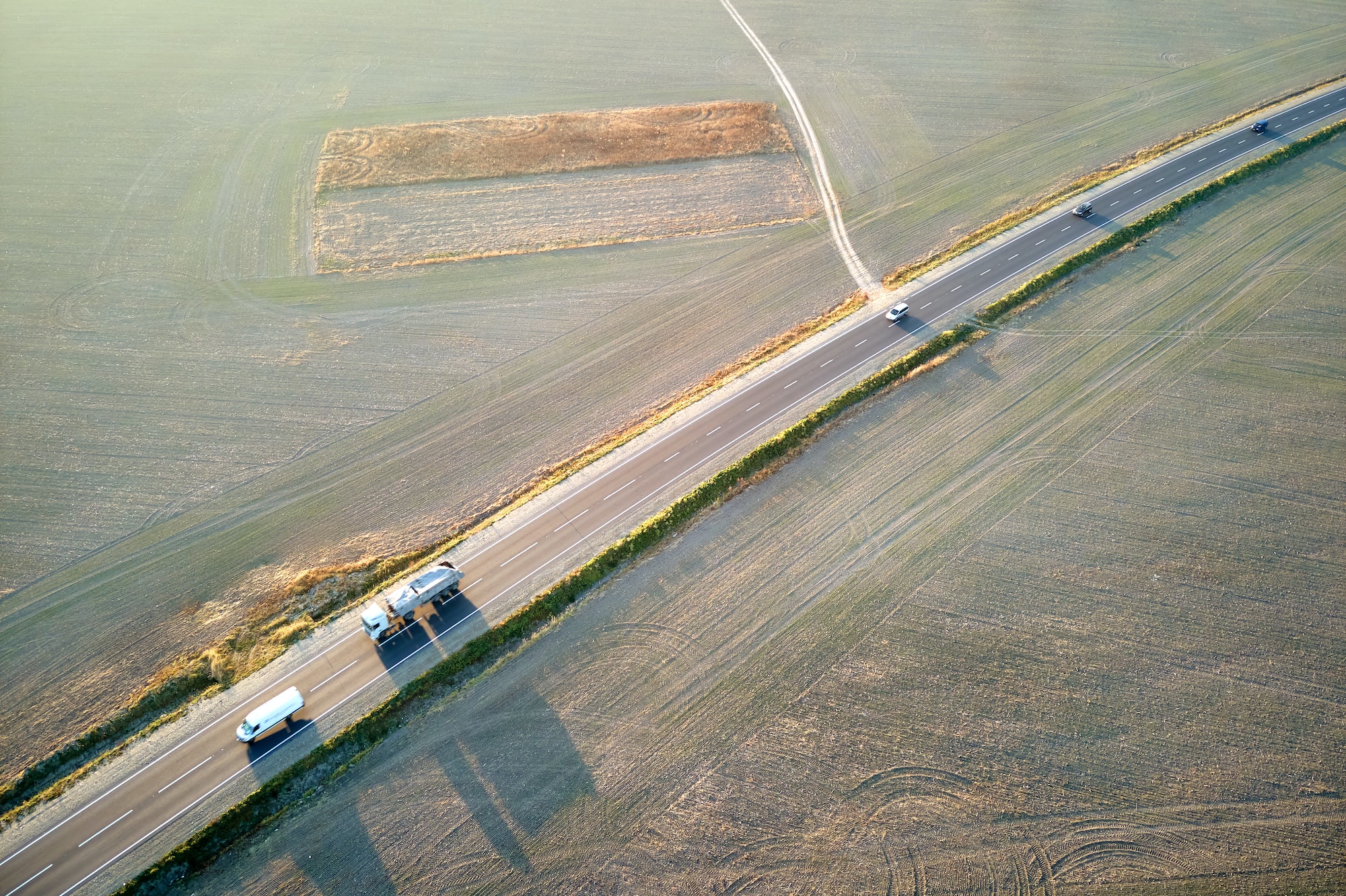 Aerial view of cargo trucks driving on highway hauling goods. Delivery transportation and logistics