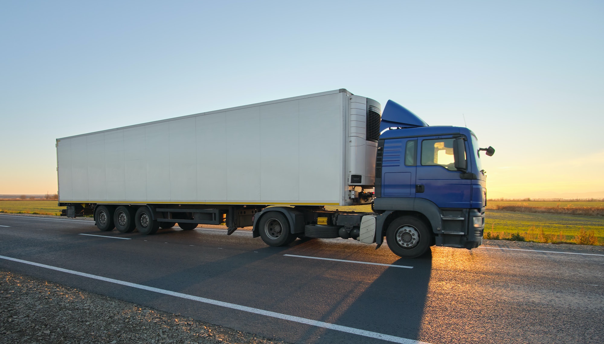 Semi-truck with cargo trailer driving on highway hauling goods in evening. Delivery transportation