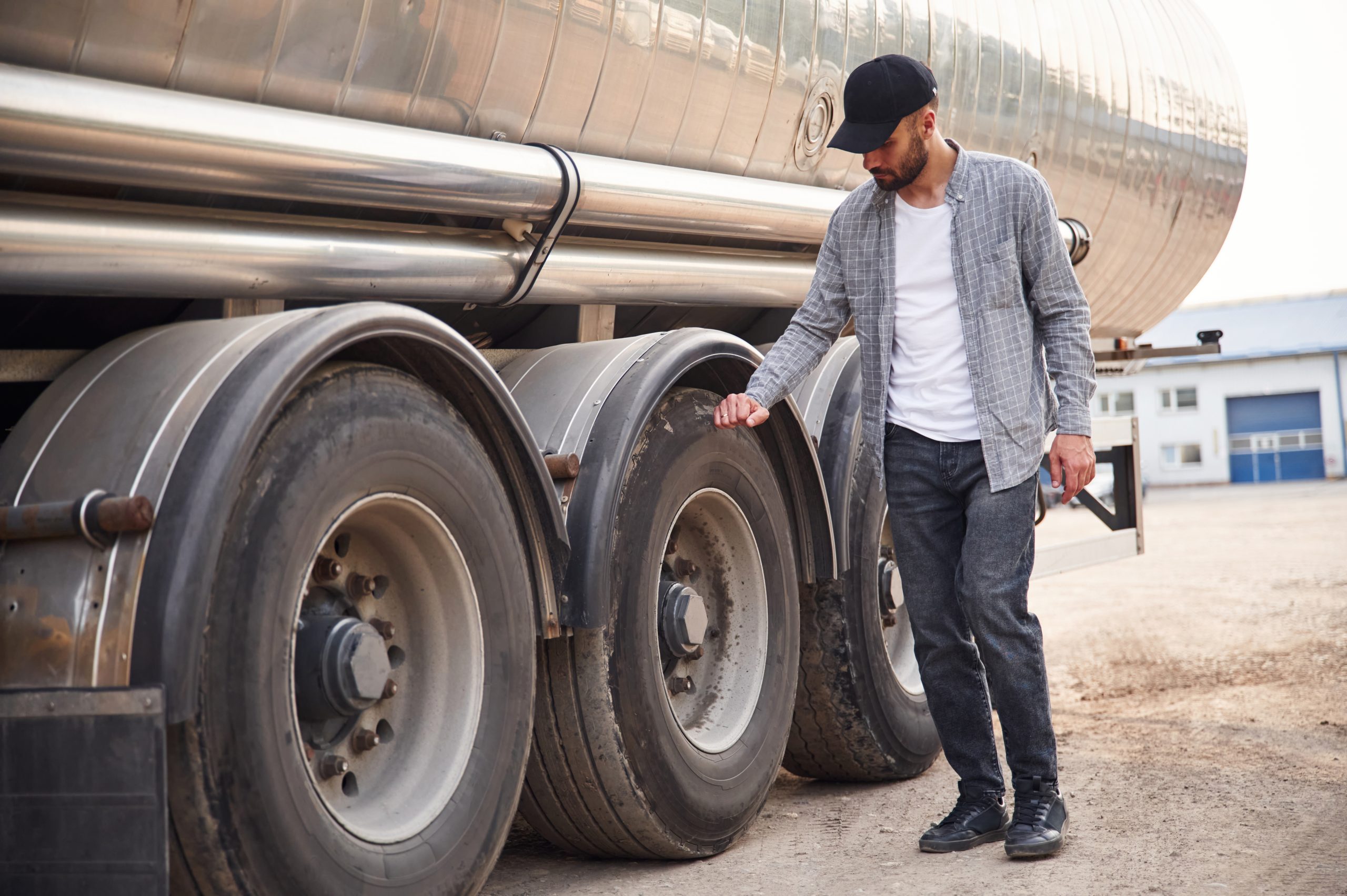 Checking the wheels. Young truck driver in casual clothes